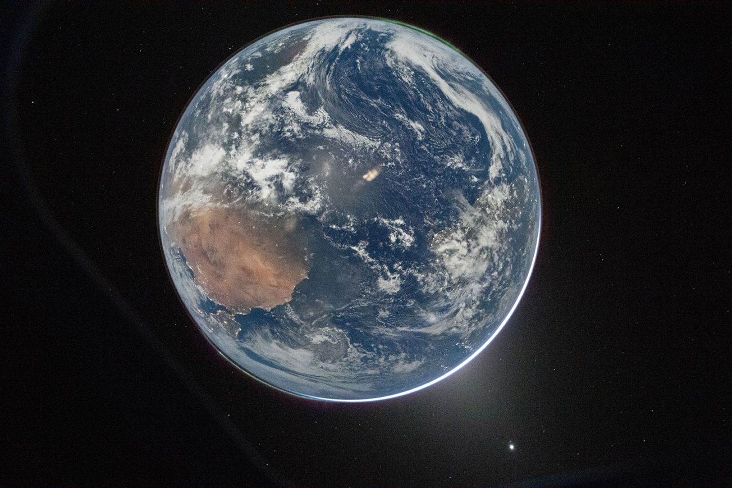 The Earth at night seen from the Artemis II spacecraft, lit by the full Moon, with Venus as a bright dot